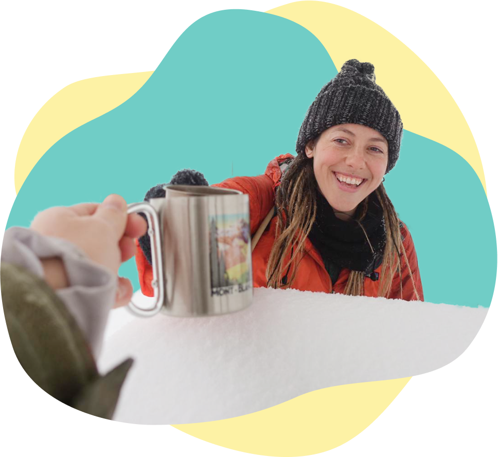Meg smiling clinking coffee mugs with friend in snowy outdoors
