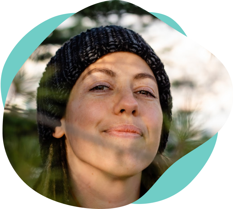 Closeup of Meg smiling at camera surrounded by pine trees