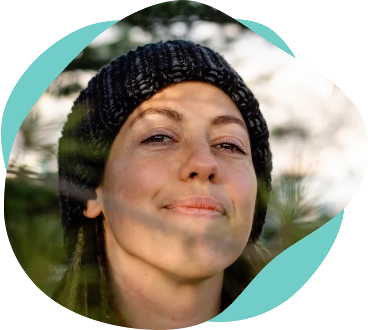 Closeup of Meg smiling at camera surrounded by pine trees